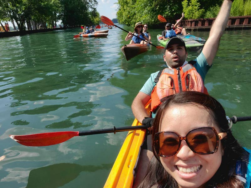 student with arm raised kayaking
