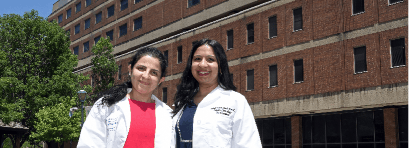 Two Pediatric Neurologists standing and smiling in white coats.